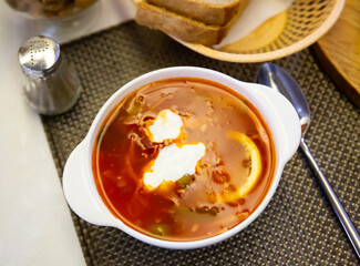 Popular meat soup of Russian cuisine Solyanka with sour cream and lemon