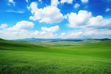 Obraz premium Lush green field under a vibrant blue sky. Rolling hills and distant mountains complete the landscape