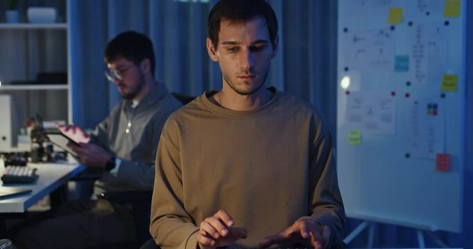 Team adult male freelance developer work late typing write prompt AI bot app program nomad terminal code at office night. Artificial intelligence dashboard, robotics, user interface, machine learning.