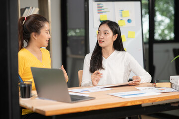 Obraz premium Businesswoman sitting in a meeting, talking about a document and chart placed on the table.