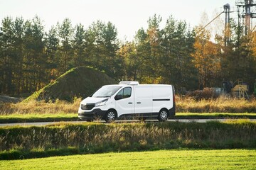 Cargo van passing by grass and factory