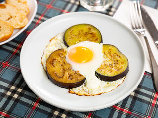 Delicious fried eggs, cooked with sliced and fried eggplant, served with bread