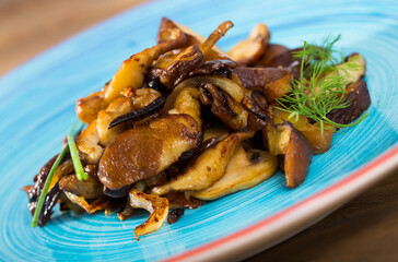 Close-up image of appetizing fried shiitake mushrooms with onion and dill served on plate