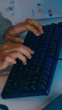 Vertical Screen : Closeup young adult Asia male freelance typing write prompt AI bot app program nomad, video game, terminal with coding language, big data center on desktop computer in night office.