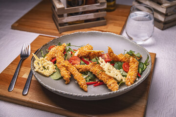 Breaded chicken strips topping fresh green salad
