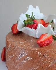 Close-up of a chocolate cake decorated with a white caramel bowl with fresh strawberries. Poster for a pastry shop, cafe