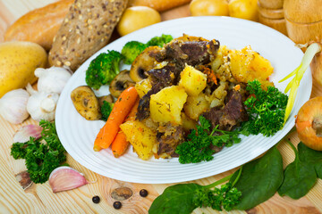 Tasty juicy fried beef served with mushrooms, vegetables and greens on plate