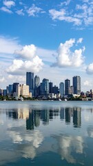 Obraz premium Serene City Skyline Under a Bright Sky with Reflective River View