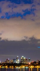 Fototapeta premium Vibrant City Skyline at Dusk with Bright Lights and Clouds