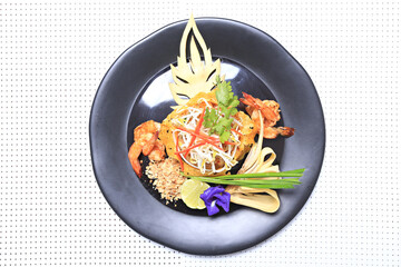 Shrimp Pad Thai, traditional Thai dish with stir fried rice noodles, shot from above on a rustic texture