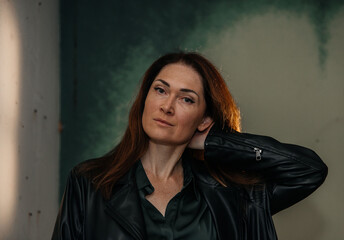Confident mature caucasian female with red hair in leather jacket