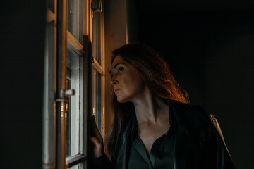 Caucasian female in deep thought looking out window at night reflection