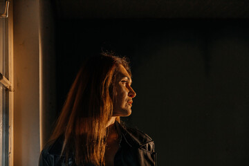 Young caucasian female gazing out window in warm light