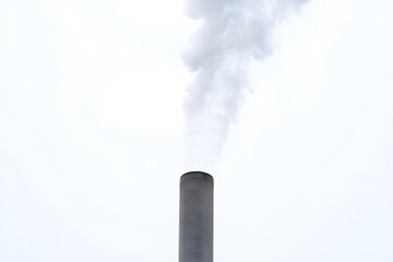 Smoke Plume from Industrial Chimney: A stark, vertical image captures the stark contrast of a towering industrial chimney releasing a plume of white smoke against a pale sky.