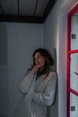 Caucasian female in cozy sweater reflecting near window in dimly lit room