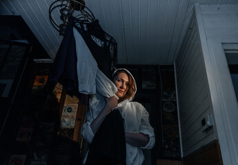 Young caucasian female in dimly lit room holding clothes in dramatic light