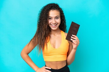 Young Arab woman isolated on blue background taking a chocolate tablet and happy