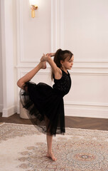 Charming little young ballerina in black dress is dancing in the studio. Girl dreams of becoming a ballerina. Concept of child development. vertical.
