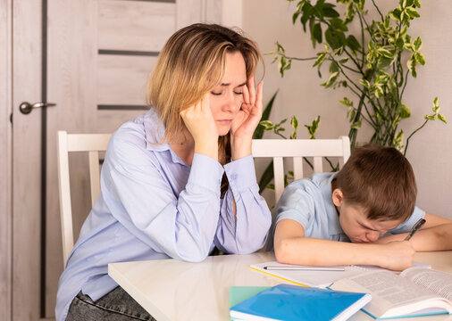 An upset, stressed child who is under stress experiences frustration while doing homework with an irritated mom at home. Problems with homeschooling.