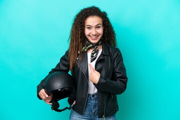 Young Arab woman with a motorcycle helmet isolated on blue background with surprise facial...