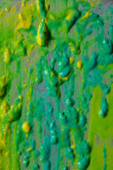 Bright green and yellow paint splashes cover the surface. The paint is thick and has a glossy...