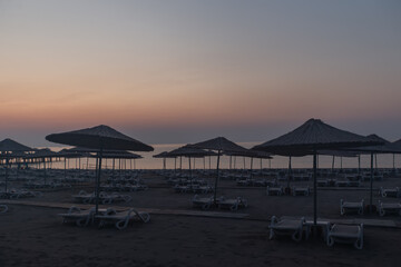 Morning beach of the resort area with empty sun loungers and umbrellas.