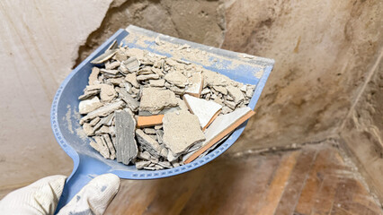 Gloved hand holds dusty remnants of bygone renovation, evoking DIY dreams, cluttered nostalgia,...