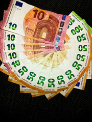 Euro banknotes of 100, 50 and 10 on a black background with copy space