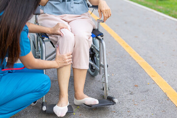 female doctor is taking an elderly person in wheelchair to relax in park help elderly person relax after elderly person injured his ankle and could not walk by himself. doctor takes patient wheelchair