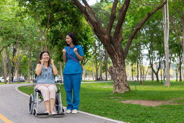 Obraz premium female doctor is taking an elderly person in wheelchair to relax in park help elderly person relax after elderly person injured his ankle and could not walk by himself. doctor takes patient wheelchair