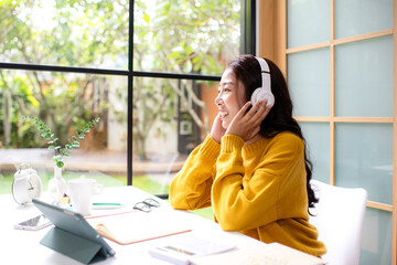 Young woman happy listen music for chill and relax after finish work.   Lifestyle girl using laptop for meeting and working  in living room at home.  Lifestyle Concept