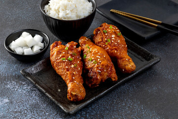 Fried chicken with Korean sauce in a black plate on the wooden table