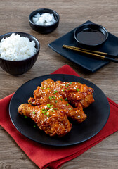 Fried chicken with Korean sauce in a black plate on the wooden table