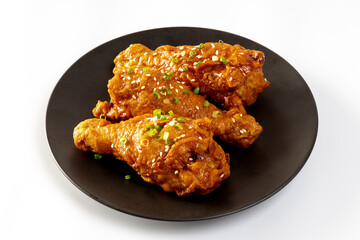 Fried chicken with Korean sauce in a black plate on white background