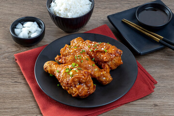 Fried chicken with Korean sauce in a black plate on the wooden table