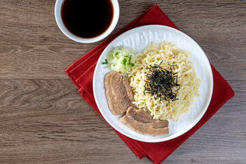 Cold ramen with pork belly on a white plate on the table.