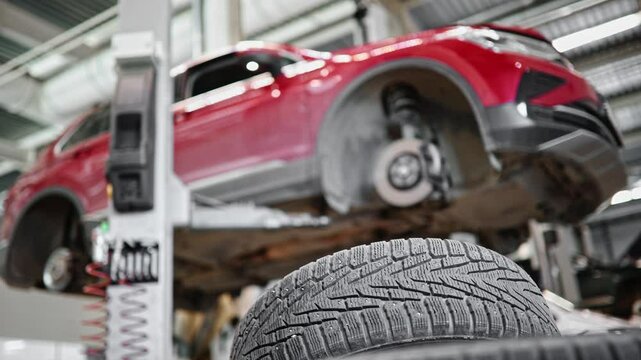 Vehicle lift for car tire replacement in auto repair shop.