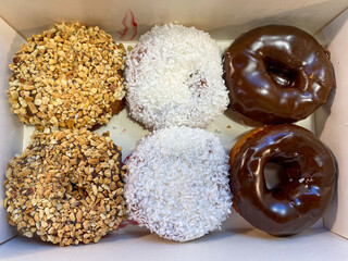 Donuts with different flavors and toppings lie in a box