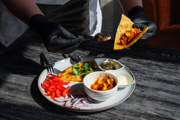 A chef wearing black gloves prepares fajitas. 