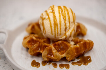 Vanilla ice-cream on the croffle, a hybrid of a croissant and waffle, served on plate with caramel sauce
