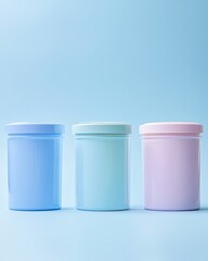 Three pastel-colored cylindrical containers, likely for cosmetics or food, stand in a row against a light blue backdrop. 