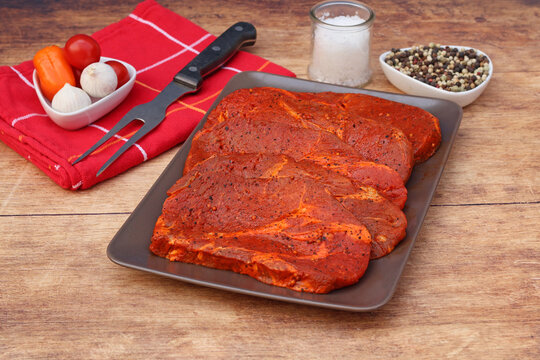 Pork neck steak arranged on a plate with spices and vegetables.