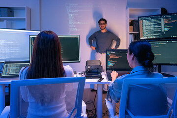 young Asian software development manager leads a late-night office discussion with his executive...