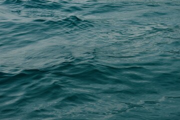 Obraz premium Gentle ripples on a serene body of water, reflecting shades of blue and green.