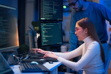 Asian programmers collaborating on software development at night, focused on writing code across multiple monitors in a tech office environment  Programmers Collaborating on Software Development 