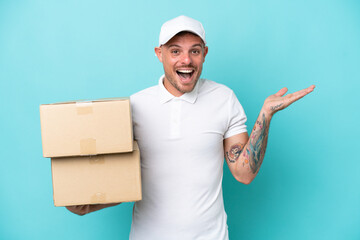 Delivery caucasian man isolated on blue background with shocked facial expression