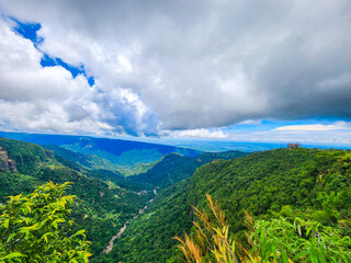 panoramic view of a lush green mountain valley under a cloudy sky