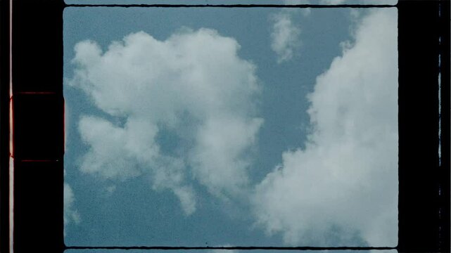 White clouds moving slowly in blue sky, super 8 film look