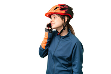Young cyclist girl over isolated chroma key background keeping a conversation with the mobile phone with someone