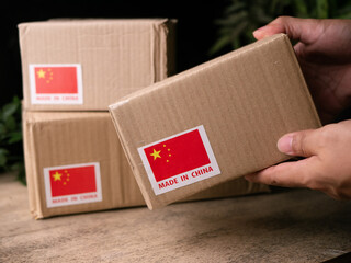 Man Hands carry shipping cardboard box with MADE IN China flag label on.